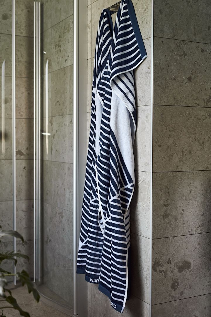 Gi bort badehåndkleet Stripes fra NJRD som en farsdagsgave til saunaelskeren; her henger det foran en dusj.