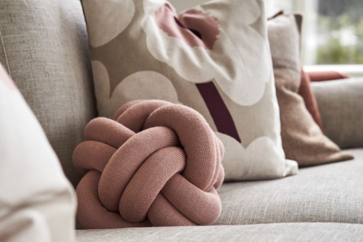 Knot liten i dusty pink på en sofa med andre puter. 
