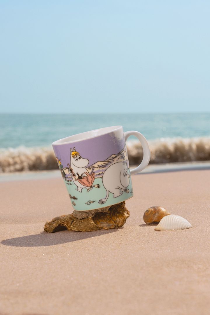 Sommerens mummikopp 2025, «Beach Day», står på en sandstrand.
