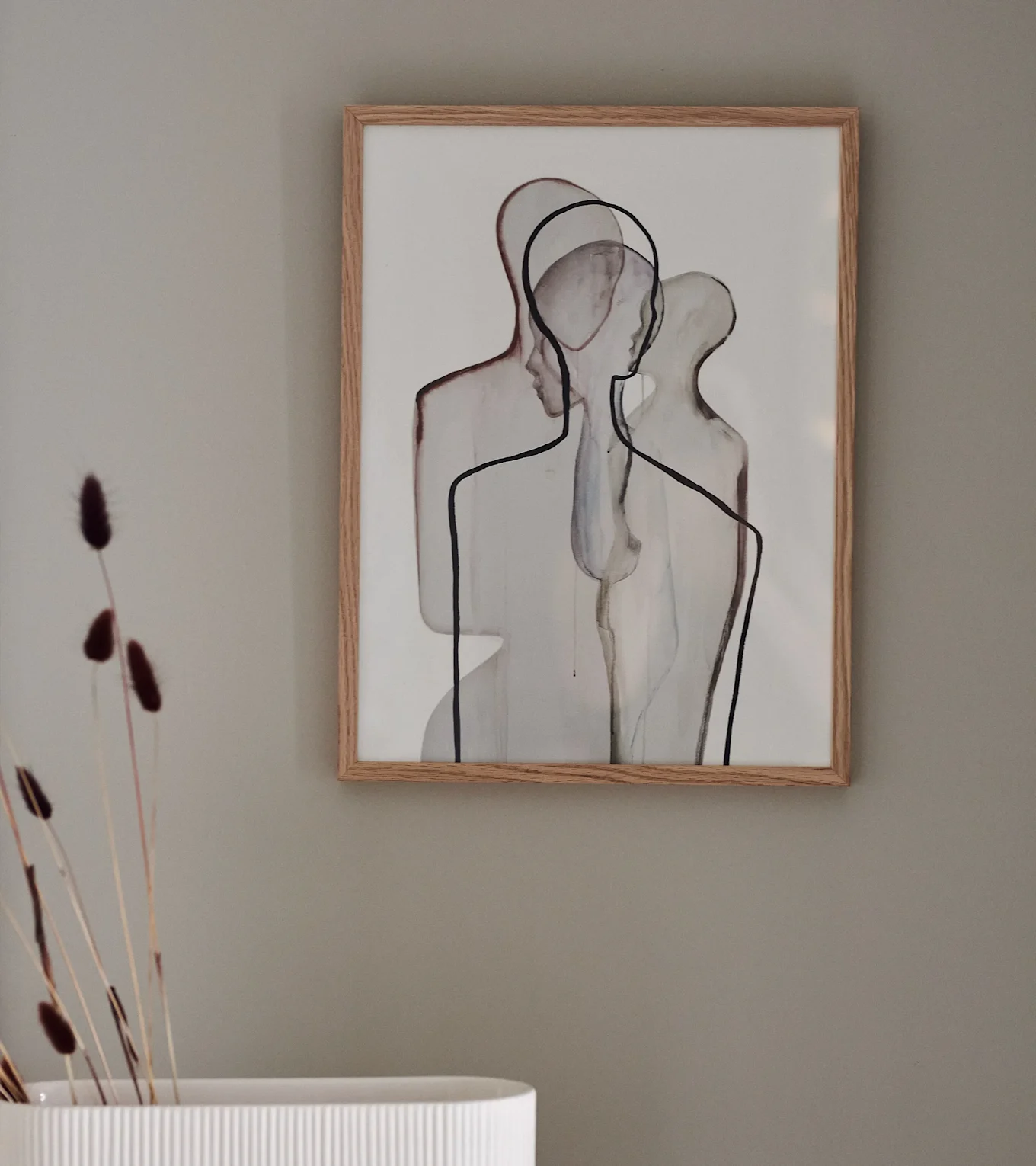 Innrammet abstrakt kunsttrykk med en oransje sol over brune bølger, lent mot en sofa på et fluffy teppe.
