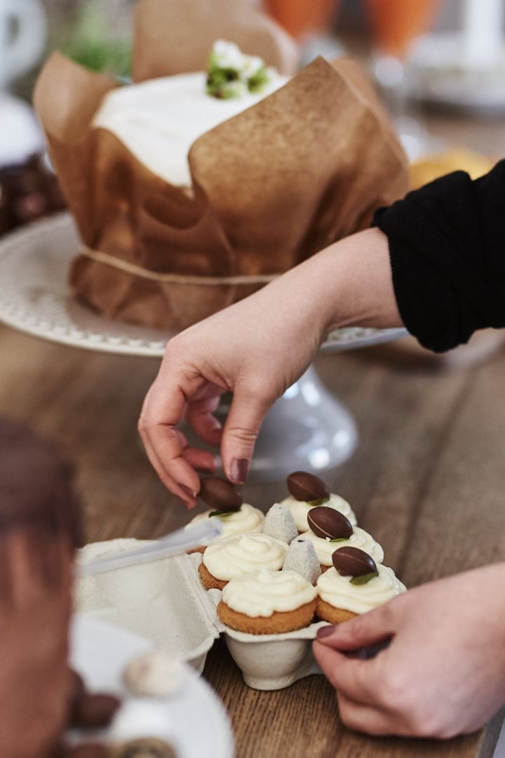 En av flere påskedesserter på dessertbordet er søte muffins dekorert med frosting og pyntet med sjokoladeegg.