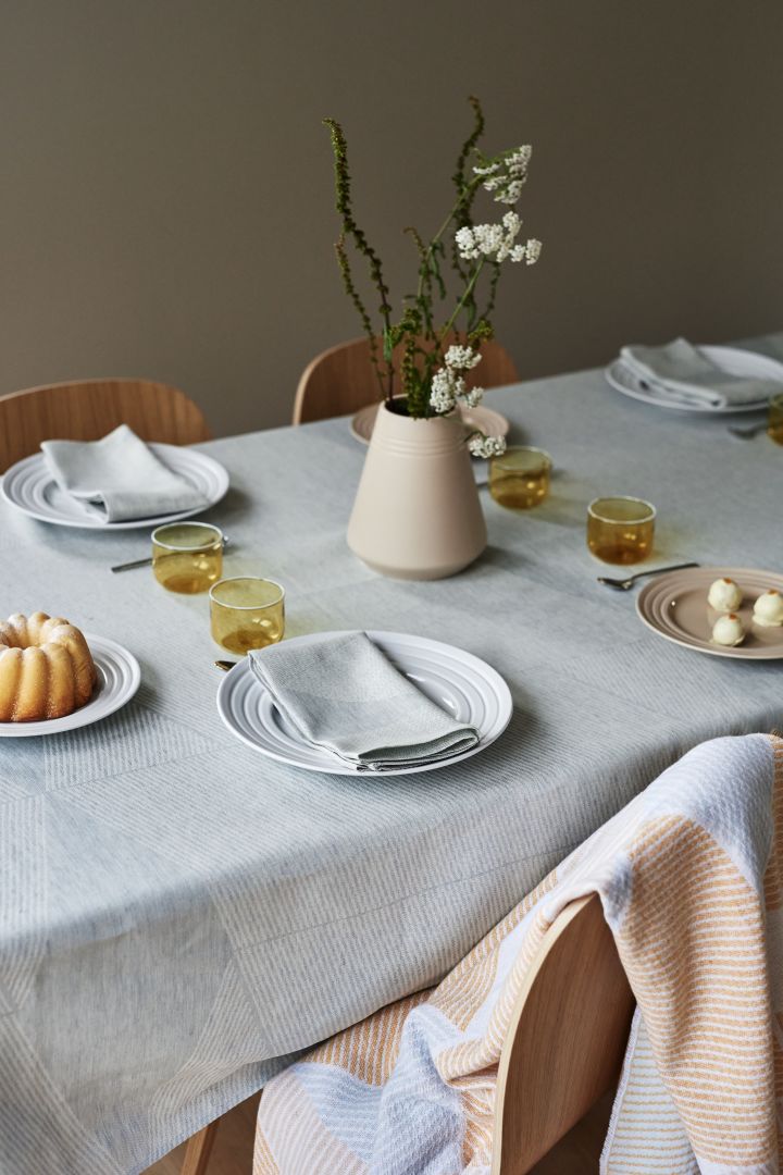 En vakker borddekking i lyseblått og pasteller med hvitt servise fra NJRD, linservietter og linduk.