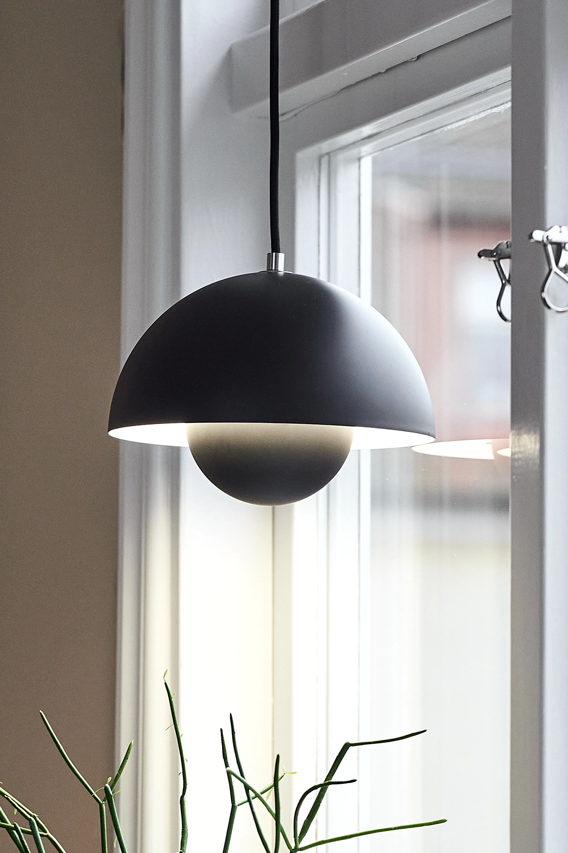 Her ser du den skandinaviske designlampen VP1 hengende i et vindu.