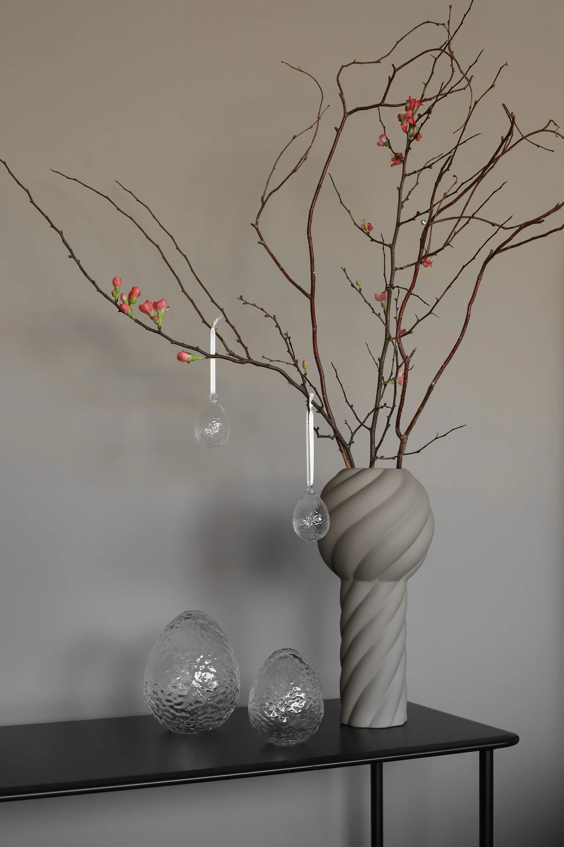 Et påskeris dekorert med transparente Gry Ei-påskeanheng fra Cooee Design – en elegant detalj når du pynter til påske.