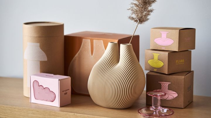Fine forpakninger til HAYs produkter ved siden av W&S Chamber vase i Light beige og Flare Stripe lysestake i rosa.