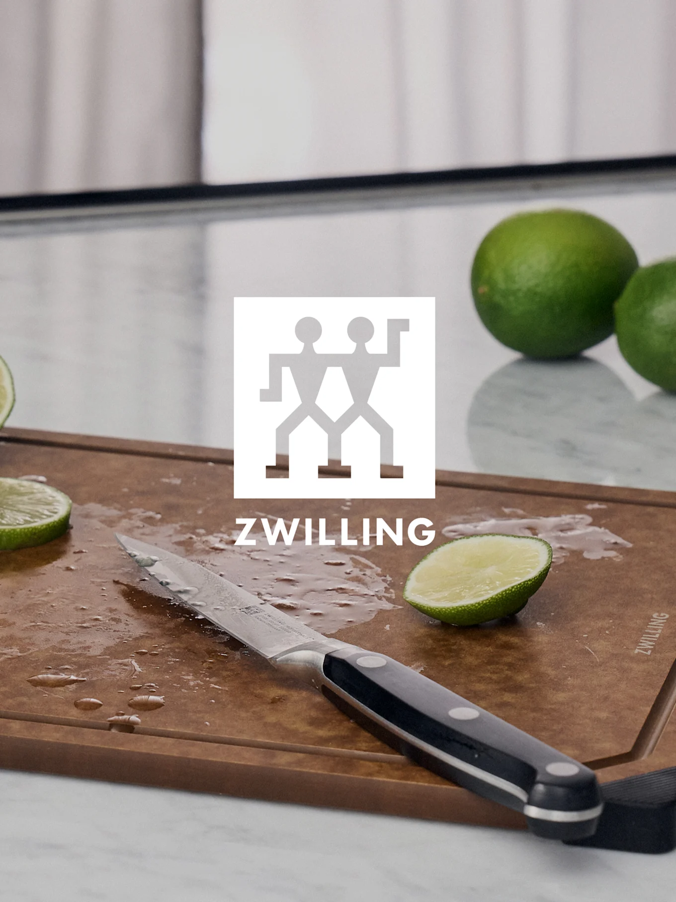 ZWILLING-logo over et skjærebrett med en kniv, skåret lime og hele lime.