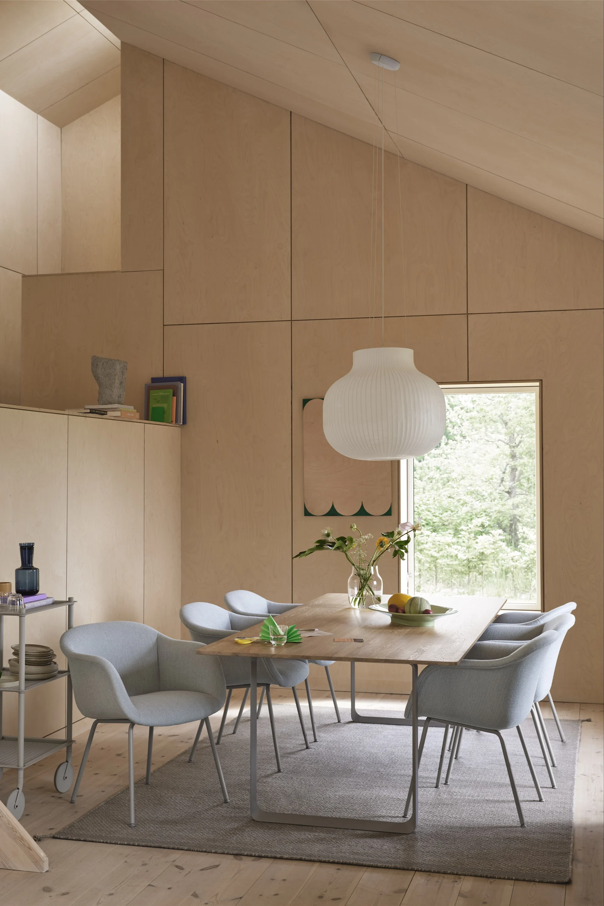 Gulvtepper til spisestuen: Det grå Ply-ullteppet fra Muuto ligger i en skandinavisk innredet spisestue med lyseblå stoler og mye treverk.