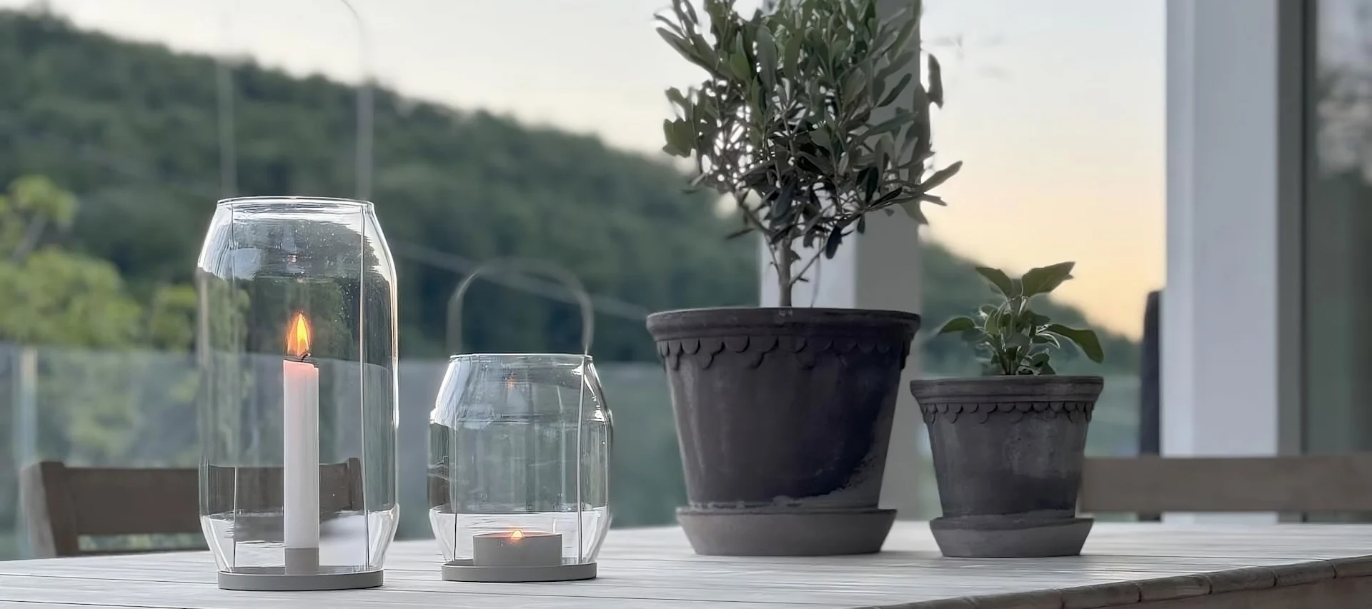 To blomsterpotter fra Bergs Potter står på et bord ved siden av to Ernst-lykter på terrassen til @zuhauselig.