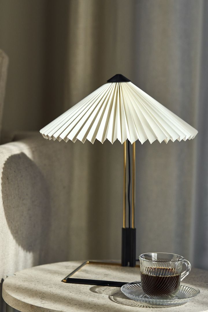 Matin bordlampen fra HAY er et tips for en trendy lampe med plissert lampeskjerm, den har en ramme i messingstål og er perfekt å ha på sidebordet.