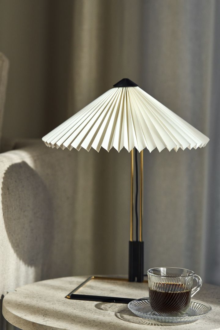 Matin bordlampen fra HAY er et tips for en trendy lampe med plissert lampeskjerm, den har en ramme i messingstål og er perfekt å ha på sidebordet.