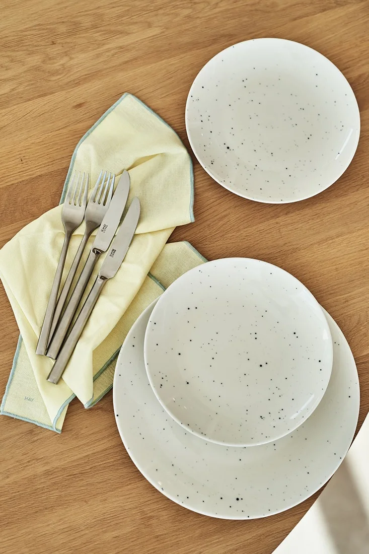 Hvitt rustikk servise fra Scandi Living og sitrongule tøyservietter fra Hay står på bordet og venter på å bli dekket til påskefeiringen.
