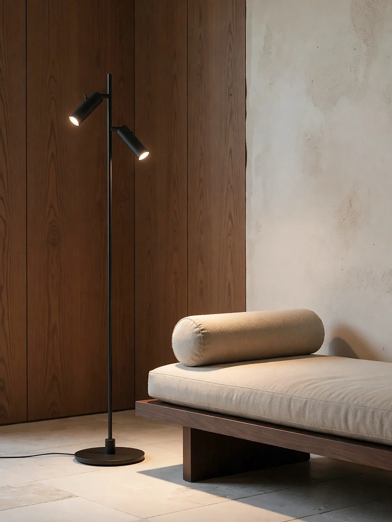 Et moderne rom med en svart gulvlampe med to lys ved siden av en tresjeselong med en lys beige pute og nakkepute.