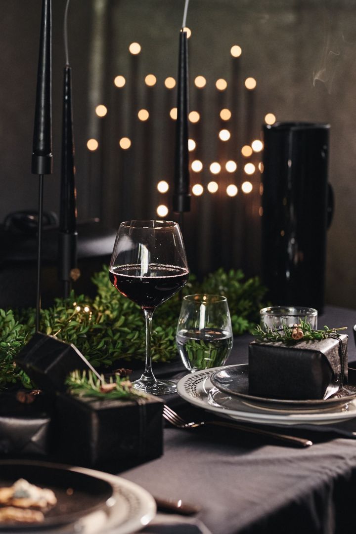 En dramatisk svart borddekking er perfekt for Halloween, men kan til og med fungere for et bryllup eller jul. Her ser du en kuvert med svarte teipede lys og svarte tallerkener fra Broste Copenhagen.