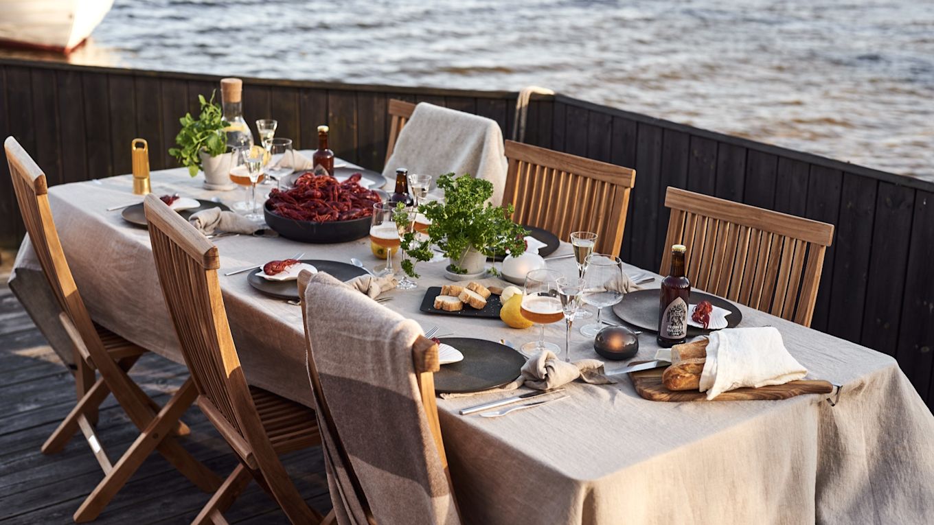 Bærbare og oppladbare lamper på sommerborddekking på brygga hvor det serveres kreps og snacks.