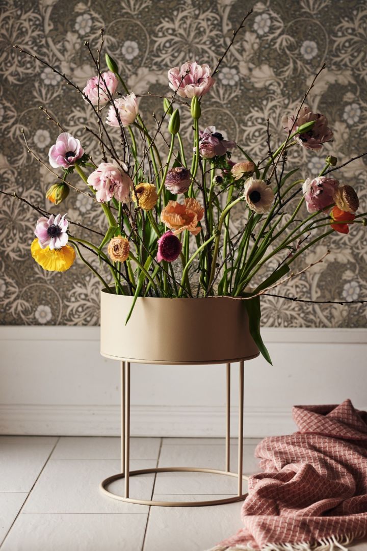 Et stort arrangement av blomster i en frittstående rund Plant Box fra Ferm Living.
