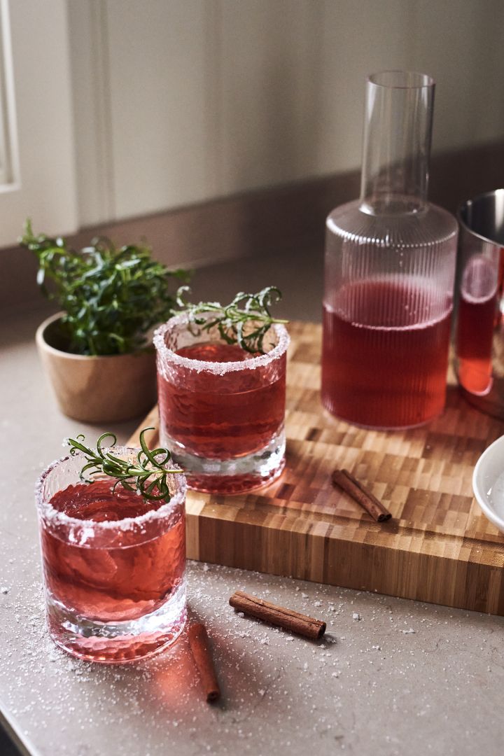 4 festlige & enkle drinker til nyttår - her ser du en frisk gin & tonic med rosmarin og agurk i et Iittala Essence-glass på en Muubs Teak-tallerken.
