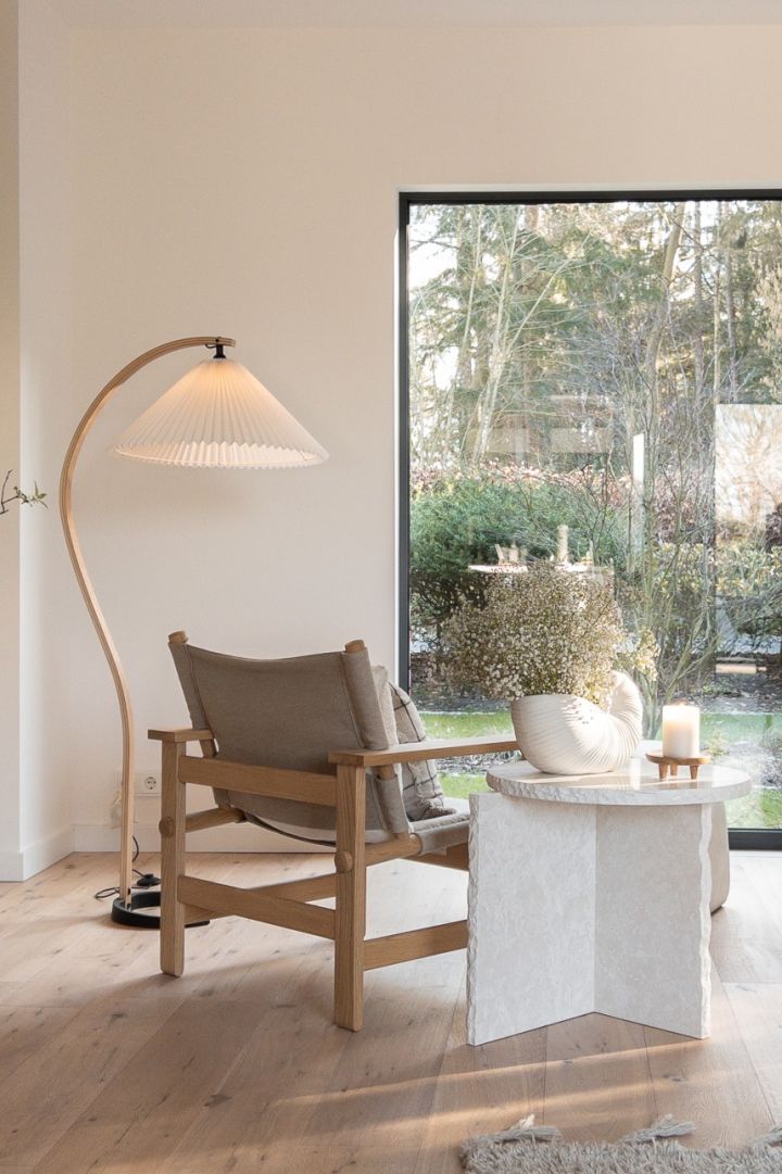 Lek med naturlig lys i ditt hjem i skandinavisk stil. Her ser du en buet gulvlampe fra Gubi og Mineral sidebordet fra ferm Living.