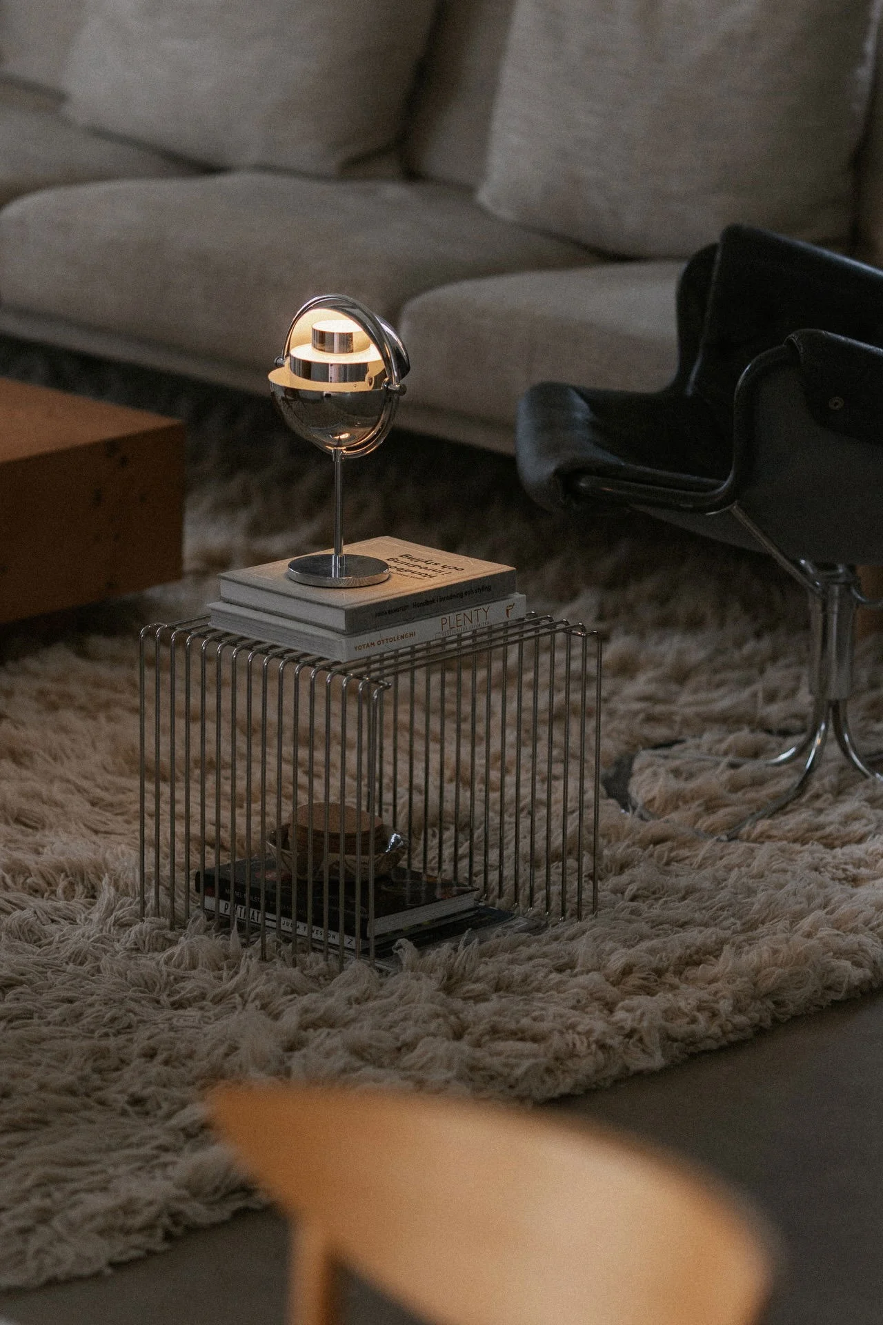 **Designlamper:** Den kromfargede Multi-Lite-bordlampen fra GUBI står på en Panton Wire-hylle i en stue.
