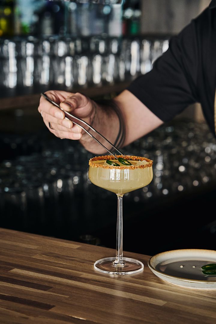 Perfekte til mocktails: Essence cocktailglass fra Iittala med en dekorert drink og jalapeñoskiver servert med tang.