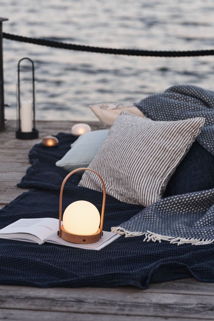 En koselig piknik på brygga blir perfekt når du tar med din oppladbare lampe – her Carrie i eik fra Menu.