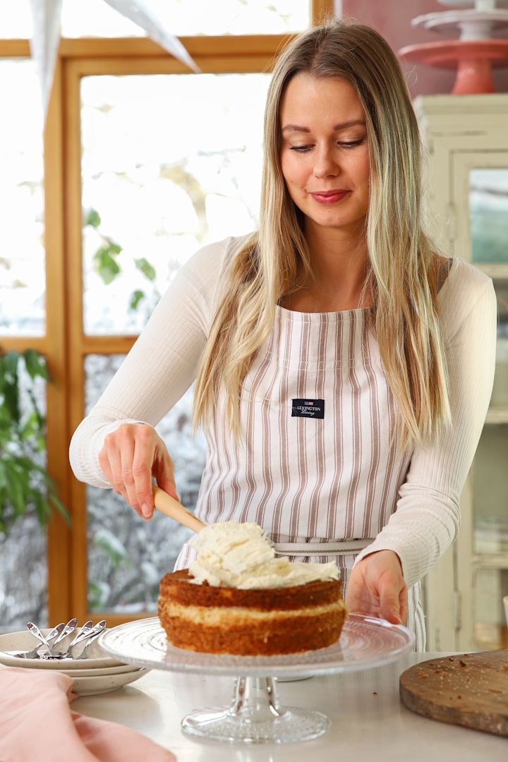 Baka med Frida til nyttår – 3 festlige bakverk å by på. Her smører Frida Skattberg god krem med en Craft-slikkepott fra Le Creuset på kaken som står på Iittala Kastehelmi kakefat.