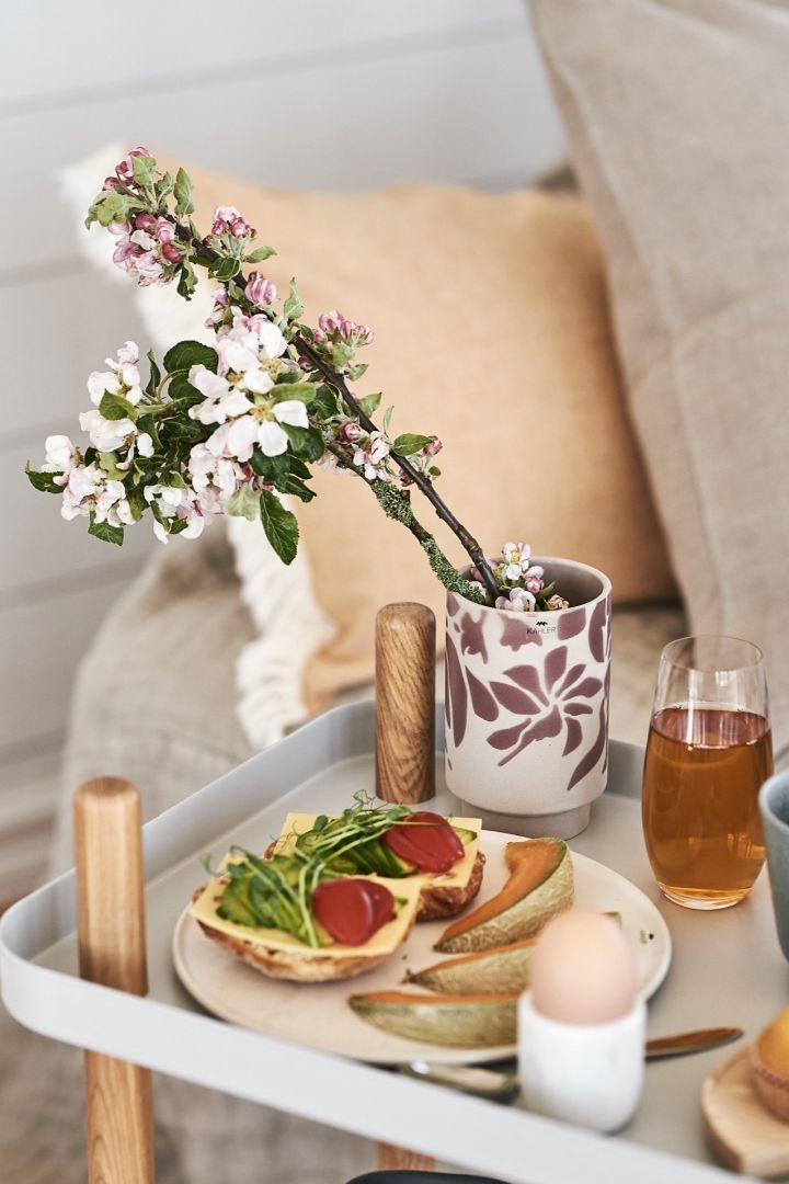 En blomstrende eplekvist ligger i en liten Kabell-vase fra Kähler, som gir ekstra atmosfære til frokosten som serveres på senga.
