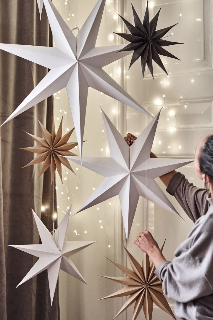 Minimalistisk juledekor med papirjulestjerner hengende fra taket i et hjem.