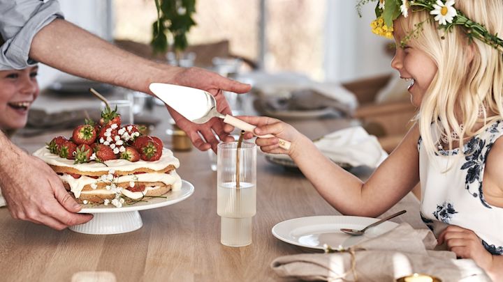 Et barn skjærer den tradisjonelle jordbærkaken på svensk midtsommer.