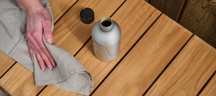 Vedlikehold teak utemøbler på beste måte ved å rengjøre dem nøye og olje dem gjerne hvis du vil beholde den rene rødbrune fargen. Her oljes stolen med spesialtilpasset teak olje og klut.