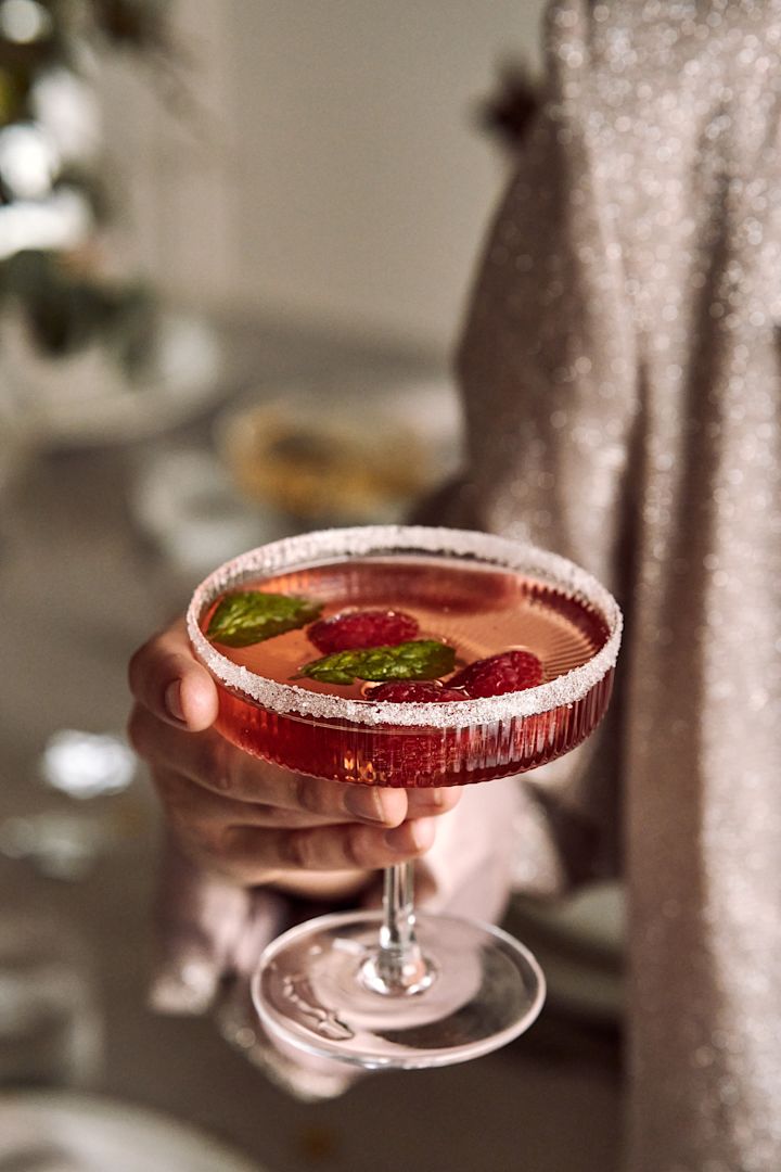 Lag en tre-retters middag til årets nyttårsbord 2023. Her ser du en festlig bringebærdrink servert i et Ripple champagneglass fra ferm LIVING. 