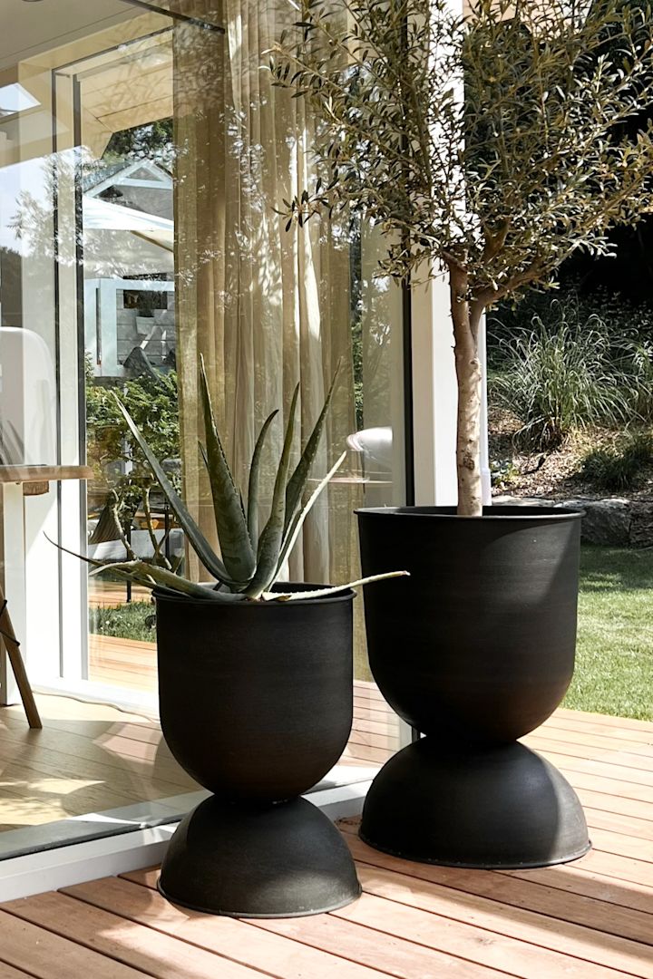 Bilde som viser en uteplass med to store Hourglass-krukker i svart metall fra Ferm Living.