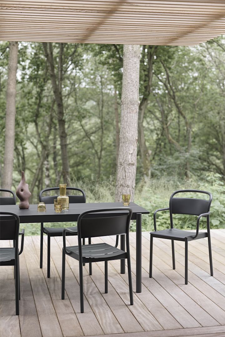 En overbygd treterrasse med bord og stoler i svart fra Linear-kolleksjonen fra Muuto.